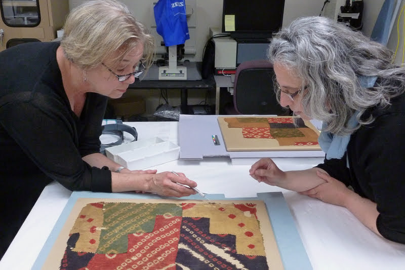 Cathy Selvius DeRoo, left, and Ruth Ann Armitage examining ancient South American textile at the Michael C. Carlos Museum.